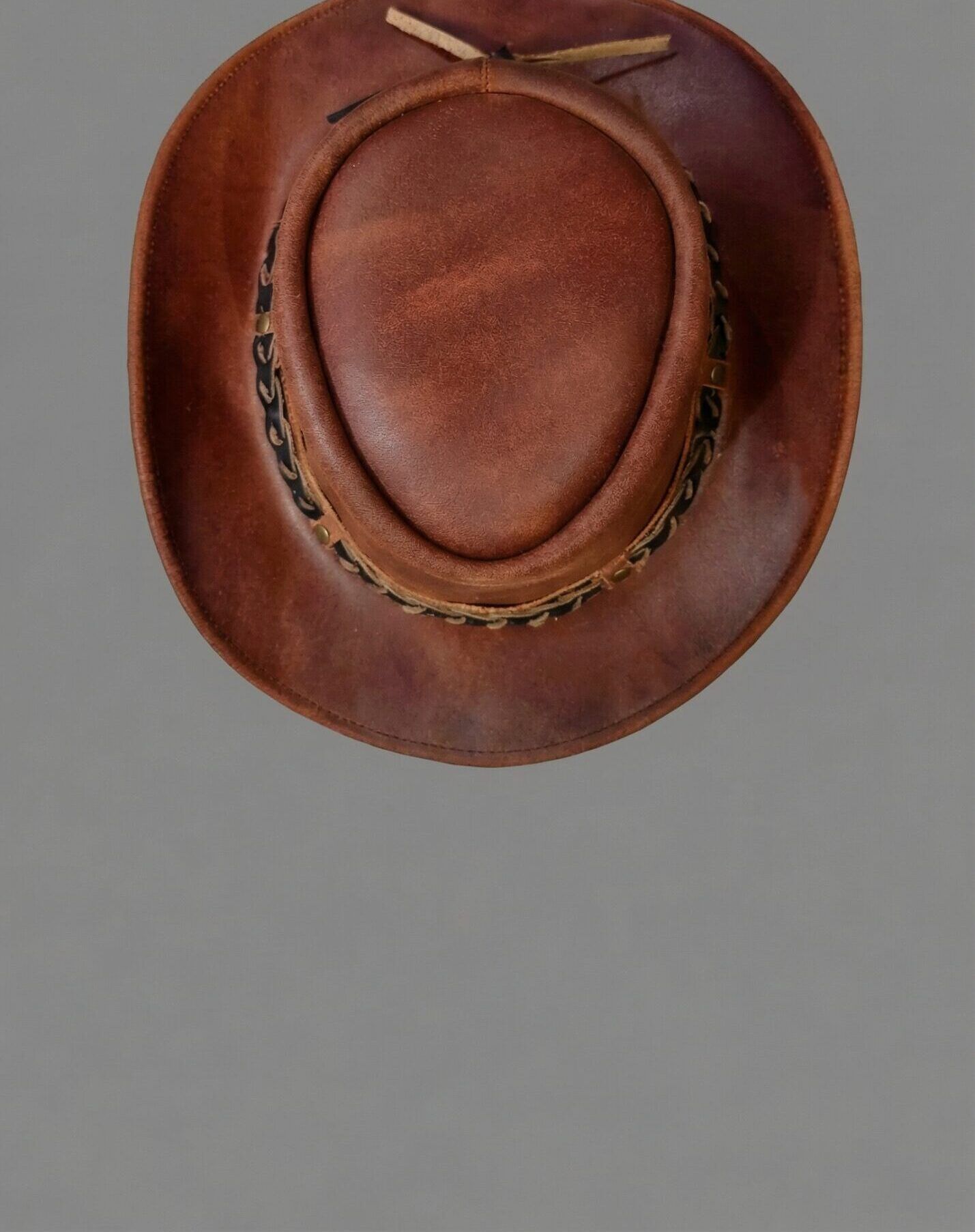 An overhead view of a cognac-outback hat showcasing rich brown tones and a braided band.