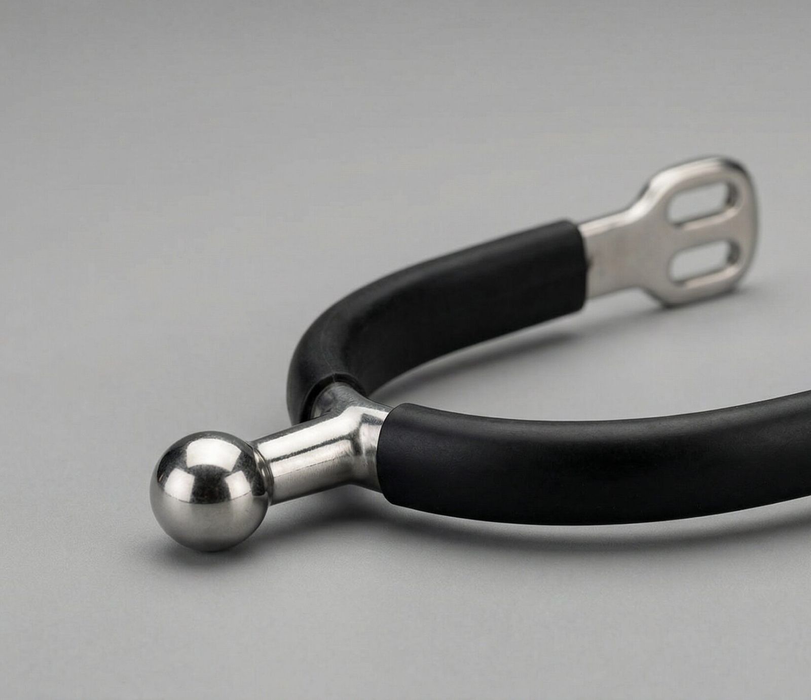 A professional horse ball spur featuring a fixed, non-rotating stainless steel ball and a protective black rubberized heel band.