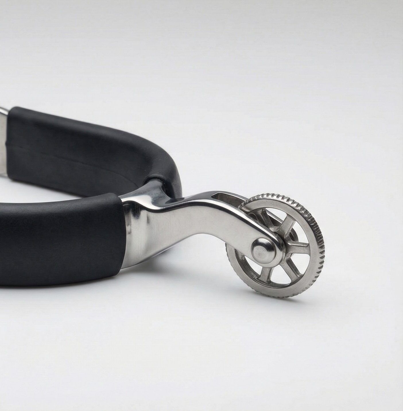 A professional stainless rowel spur featuring a rotating wheel and a black rubberized heel band.